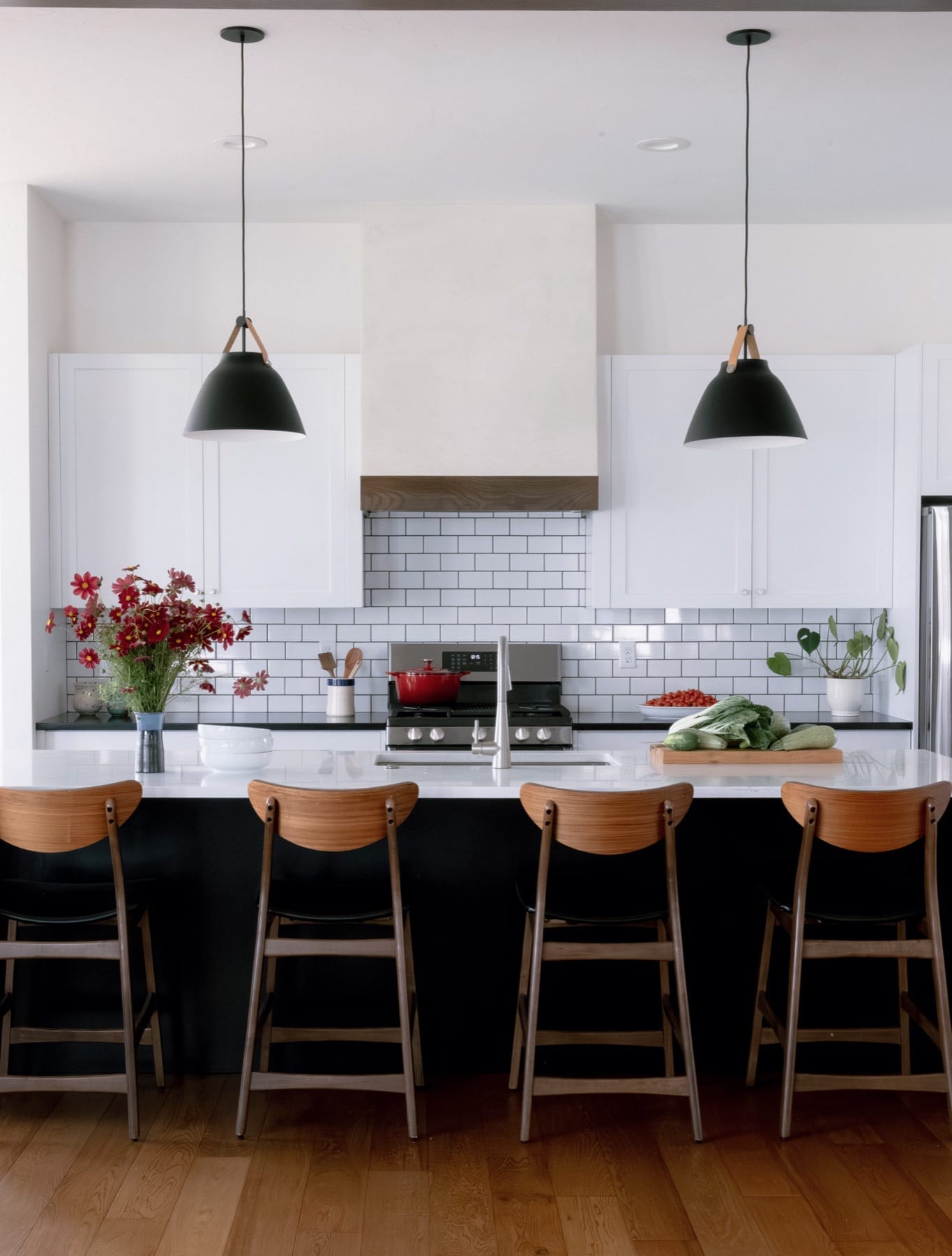 Kitchen with white cabinetry, a dark island and black pendant lights