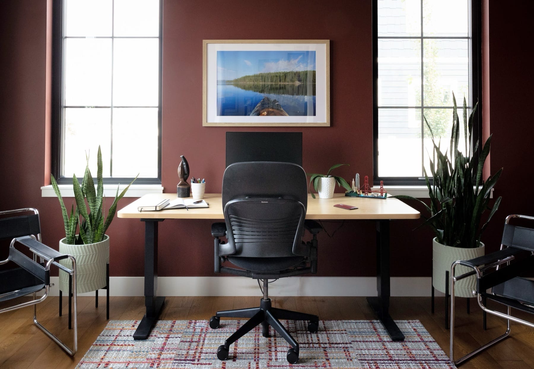 Home office with a maroon accent wall and a wood desk