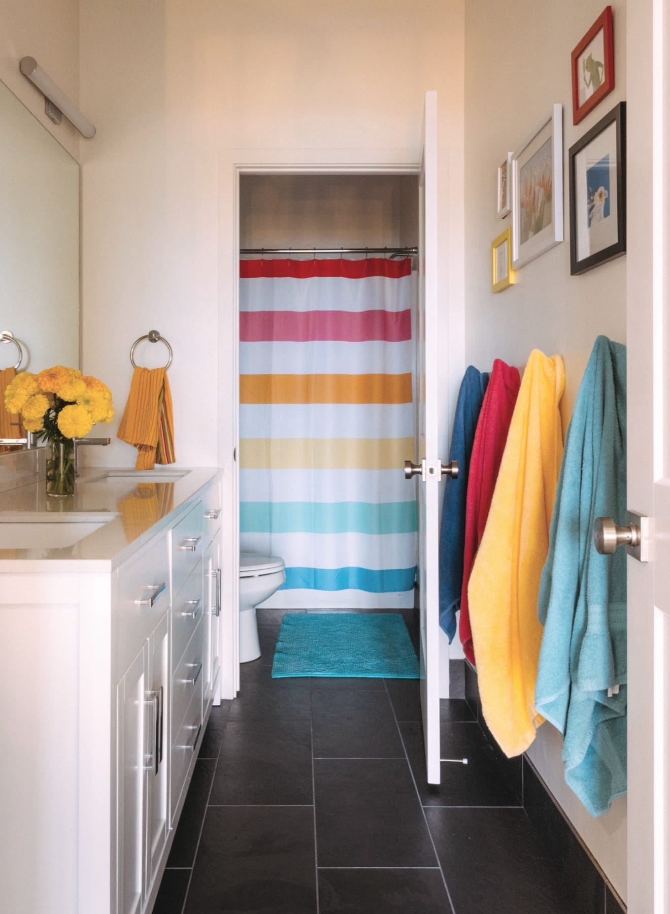 Kids' bathroom with a striped shower curtain and colorful hanging towels