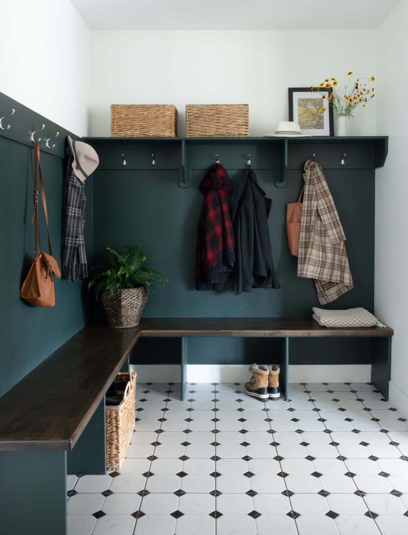 Mudroom with dark green cubbies, a bench and black-and-white tile floor
