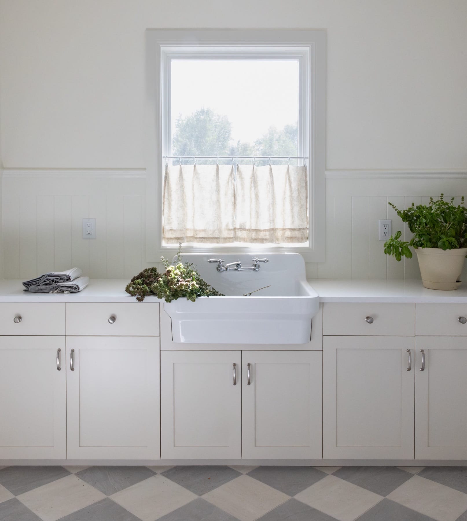 Farmhouse sink under a window with white cabinetry