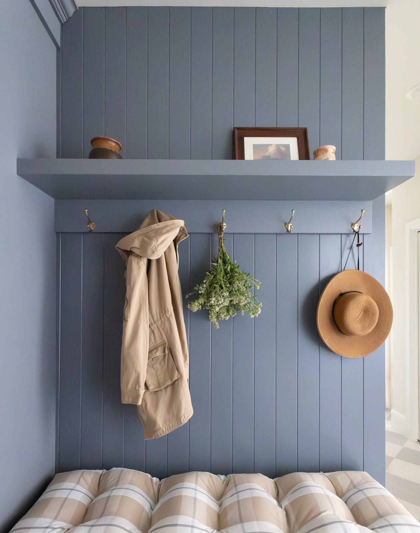 Blue-gray mudroom with wall hooks, a shelf and a straw hat