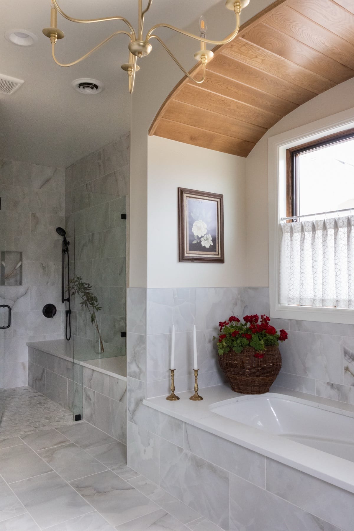 Marble-tiled shower with a window in the primary bathroom