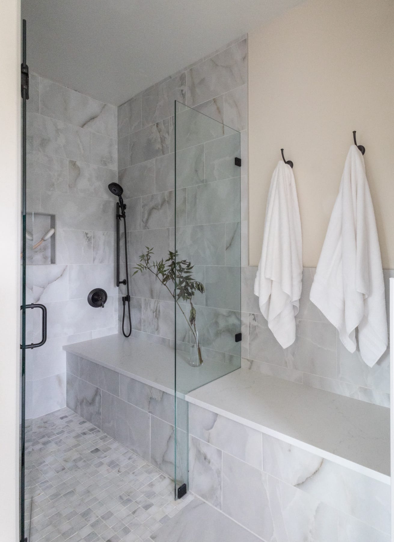Marble shower with black fixtures and hanging towels