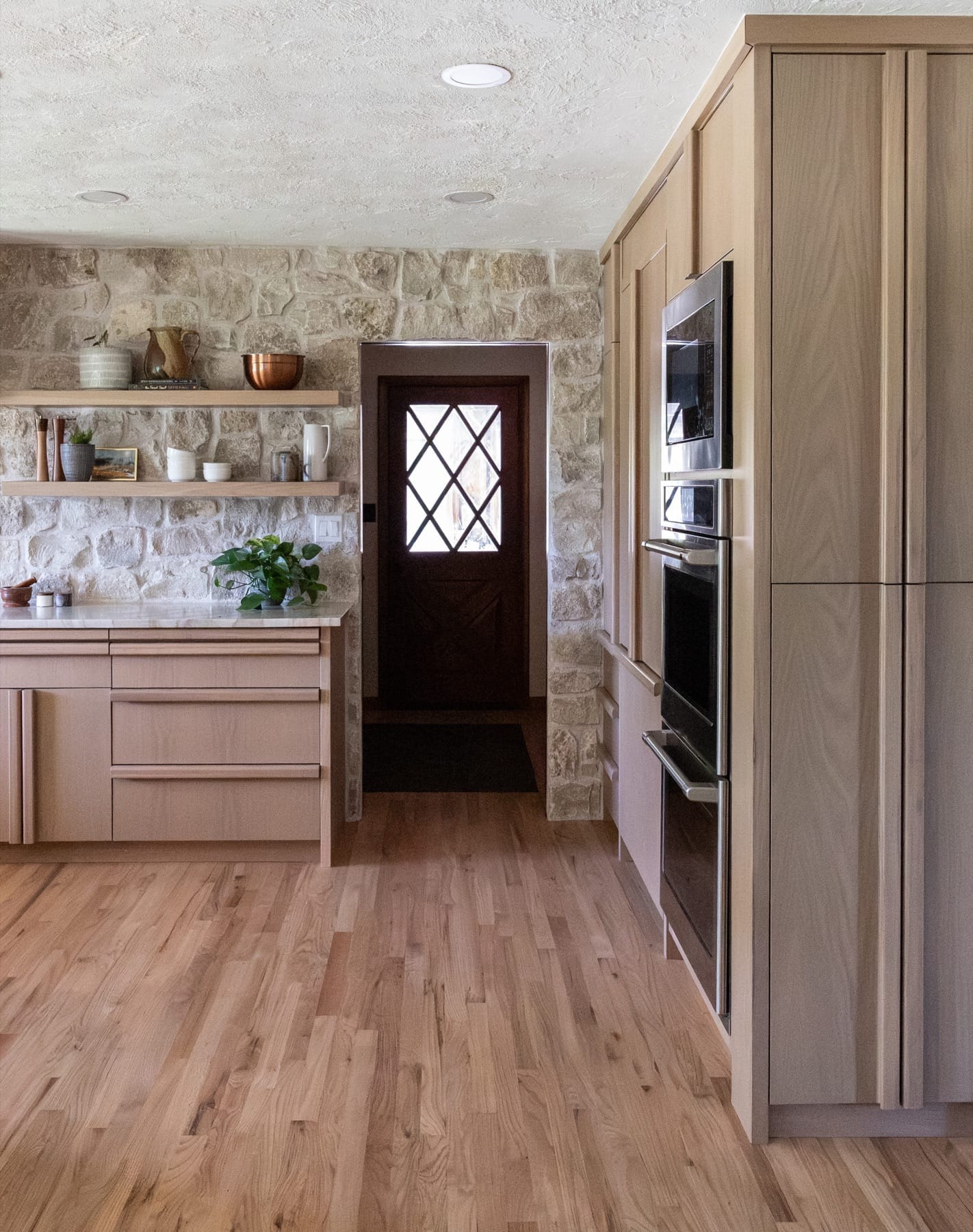 Kitchen wall oven beside a dark door with a diamond-pane window