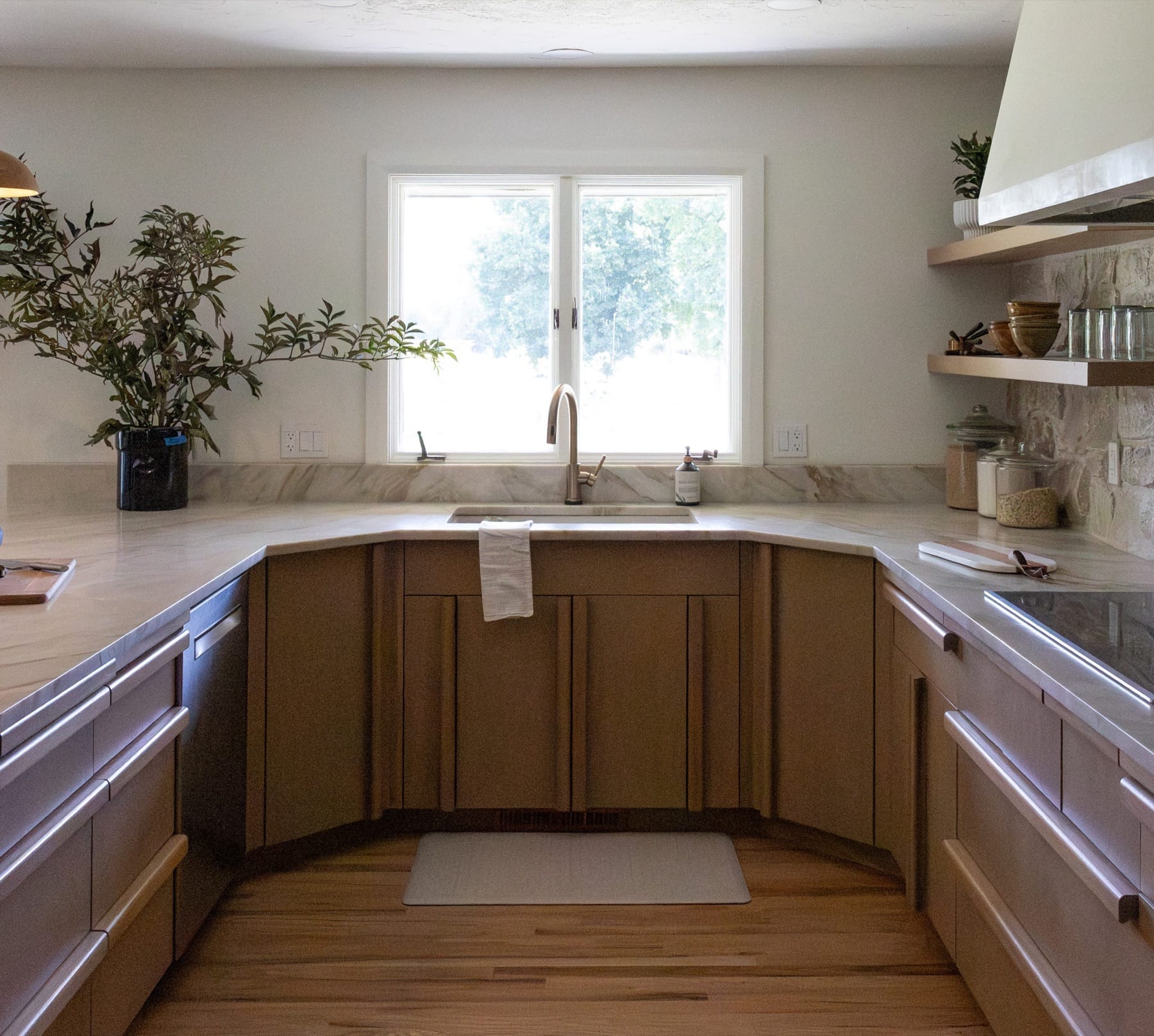 U-shaped kitchen sink area with a window and wood cabinets