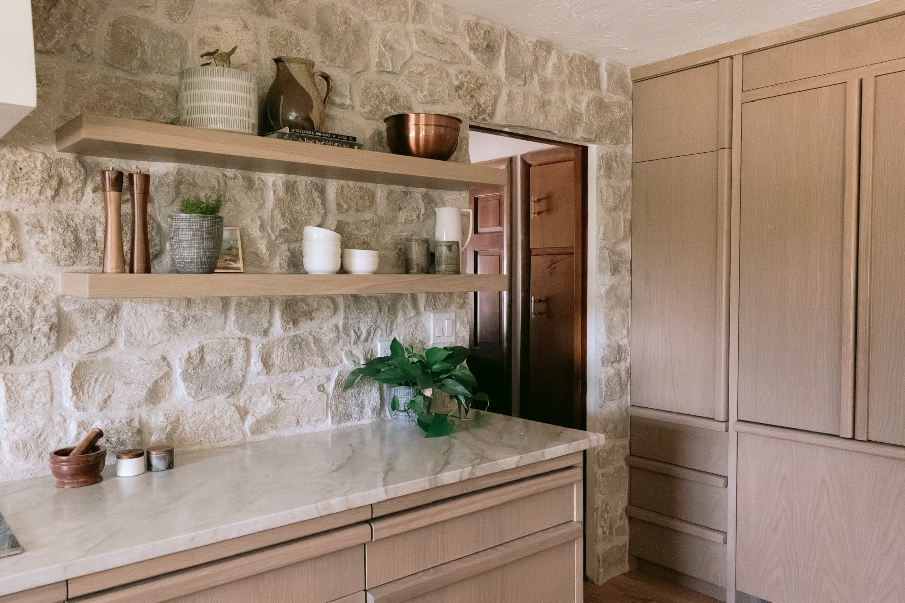 Stone backsplash and floating shelves in the Farmhouse Kitchen