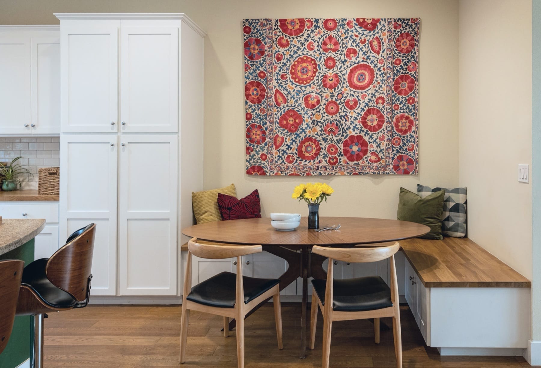 Breakfast nook with a built-in bench, round table and suzani wall hanging